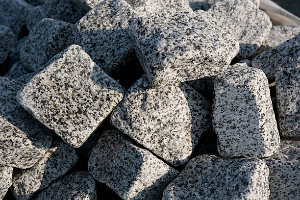 Piles of weathered granite stones bask in sunlight at a construction site.