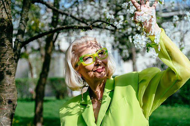 istock Confident senior woman in neon glasses interacting with blooming tree 2214704266