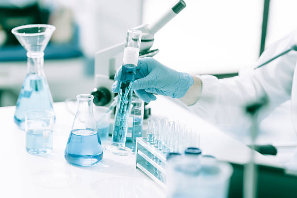 istock A white male scientist at a table, studying blue substances in test tubes and bottles, using a microscope for chemical research in pharmaceuticals, analyzing compounds for medical advancements 2214704285