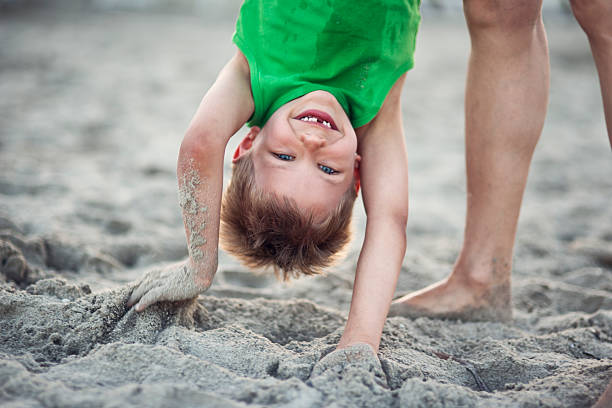 Young boy buried up to his neck in sand.
