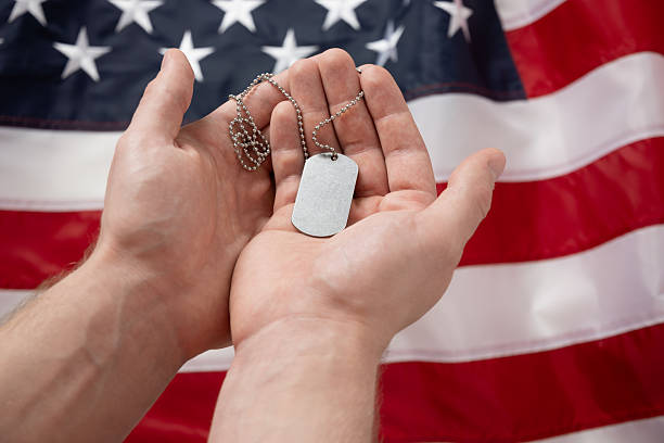 istock Hand Holding Dog Tags Against American Flag Background 2214709838