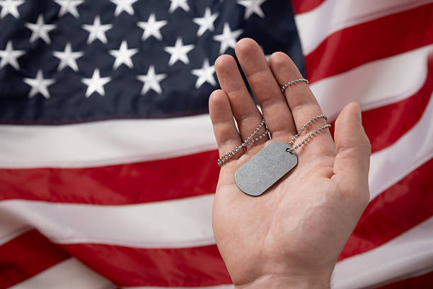 istock Hand Holding Dog Tags Against American Flag Background 2214709846