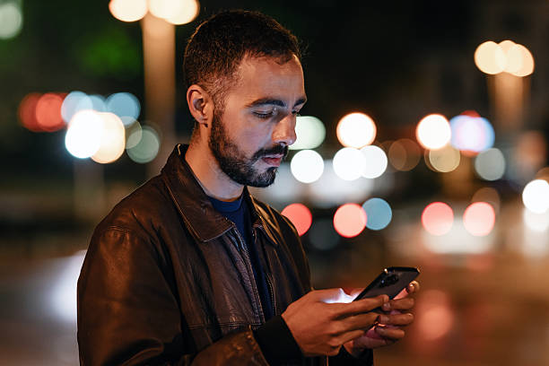 istock Young bearded man using his smartphone in the city at night 2214714831