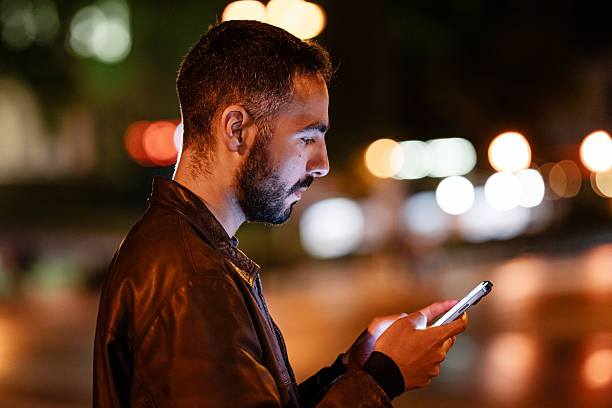 istock Young bearded man using his smartphone in the city at night 2214714842