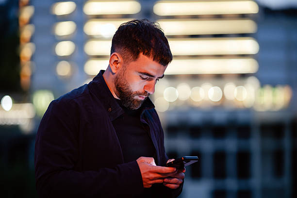 istock Young bearded man using his smartphone in the city at night 2214714862