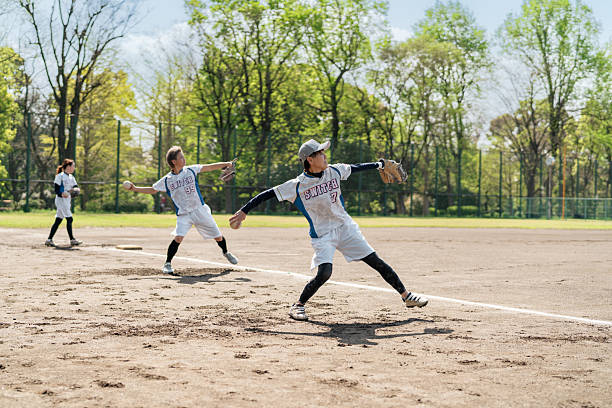 Child batter sprints toward first base after hitting the ball while catcher watches from behind home plate on a sunny summer day at a youth baseball field, energetic play and teamwork