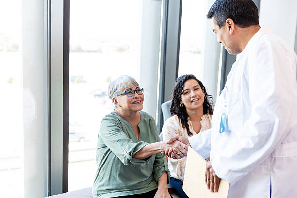 istock Doctor shaking hands with senior patient and daughter 2214715928
