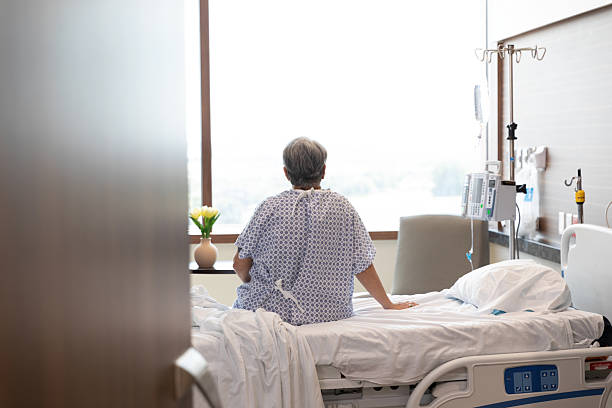 istock Patient Sitting on Hospital Bed Facing Window 2214715964