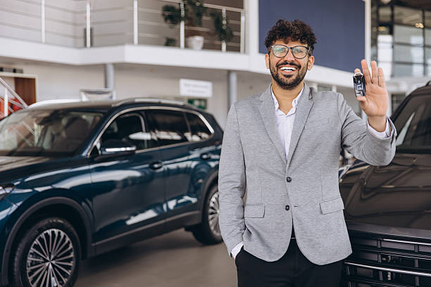 istock Smiling Man Holding Car Keys in Showroom 2214716102