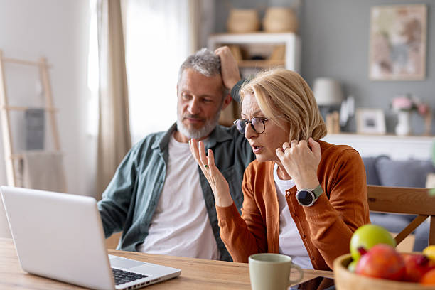 exasperated couple discussing a computer problem at home - witteboordencriminaliteit stockfoto's en -beelden