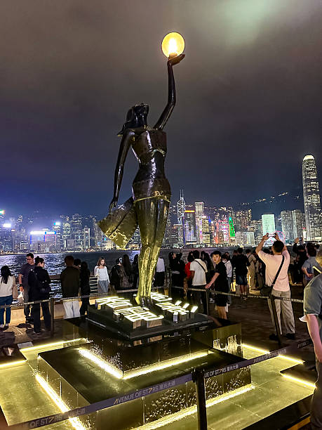 Tourists are enjoying  night time Symphony of Light and Sound show in Hong Kong Island and Victoria Harbour from Kowloon on a spring evening.