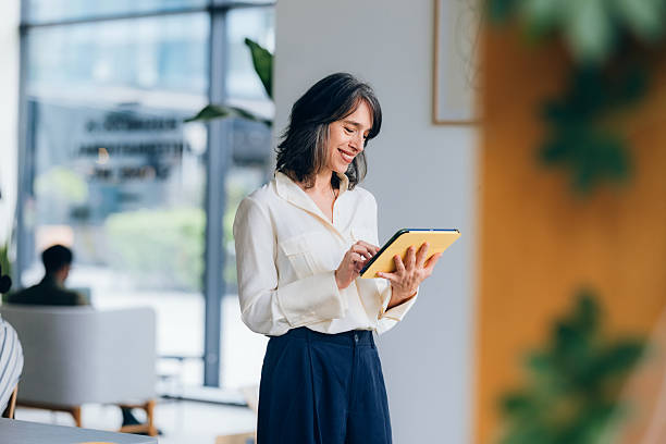 Smiling Professional Woman Using a Tablet in a Modern Office Setting