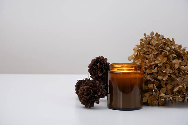 istock A glowing amber glass candle placed next to an artificial bronze flower mini chrysanthemums. 2214729797