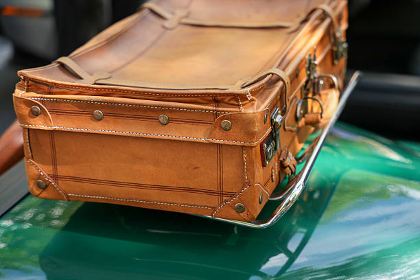 An orange vintage suitcase stands on line close-up, evening light falls on it.There is bag in center of composition,and there is another one at back. High quality photo
