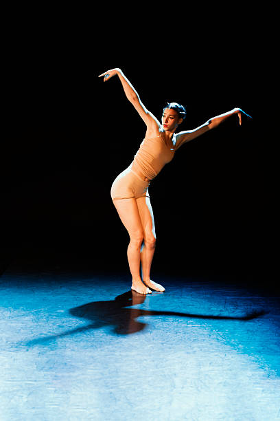 istock Young woman dancing contemporary dance on a dark stage 2214737703