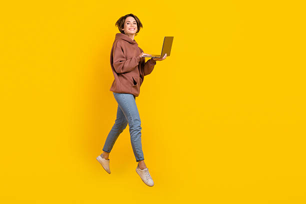 istock Full size body photo of jumping programmer girl using netbook working remote no limits freelance job isolated on yellow color background 2214737906