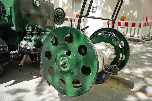 A large green hose reel. A hose reel with a coiled fire hose on a historic fire truck, displayed outdoors.