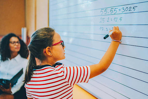 istock Schoolgirl writing on whiteboard in classroom 2214738643