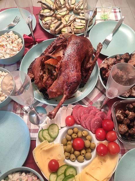 festive table setting with whole duck chicken and turquoise plates slicing sausage cheese meat glasses holiday family dinner, olives