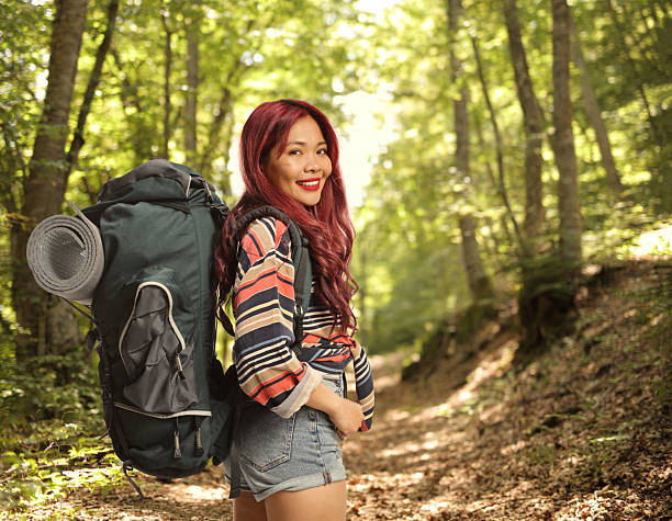 Asian female hiker with a backpack posing in the woods