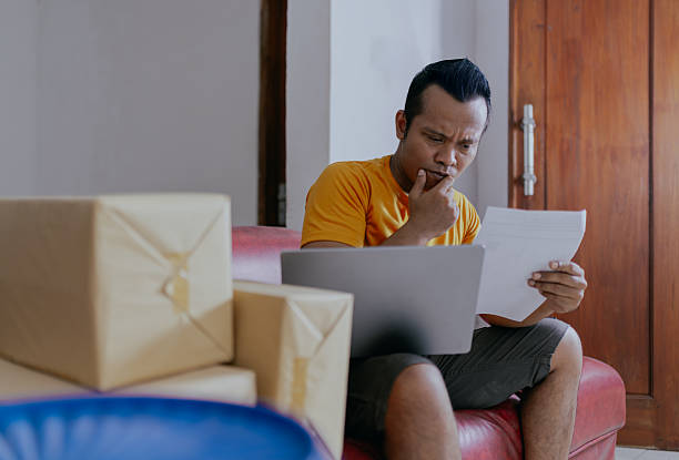 istock Pensive asian businessman analyzing documents and using laptop while working in home office. 2214742353
