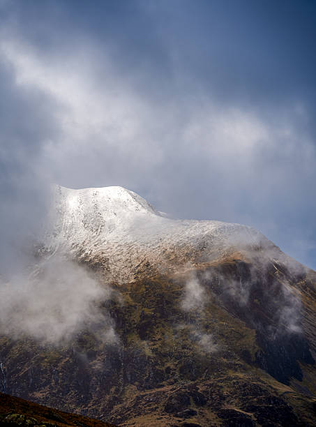 istock A lofty Glyderau summit materialises through drifting clouds, revealing a glistening snowcap against the wild North Eryri sky 2214744404