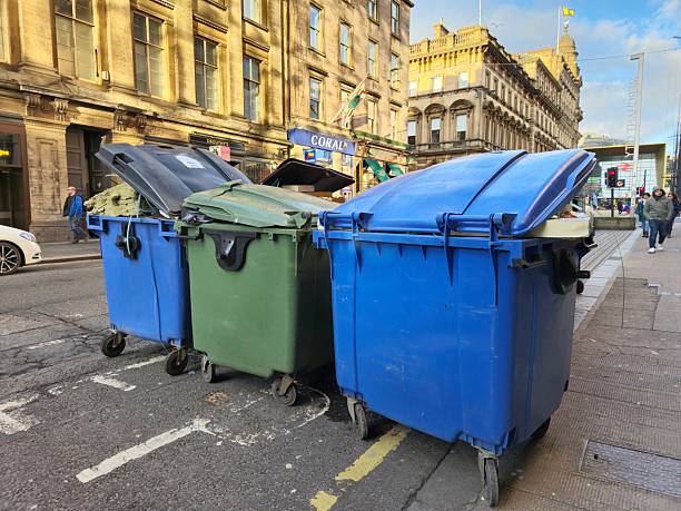 Glasgow, Scotland, UK - January 29, 2025: General waste and recycling bins at a street in Glasgow. At the background old stone buildings and Glasgow Queen Street Station with glass facade