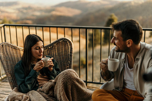 istock Couple enjoying hot drinks on balcony with scenic view 2214752077