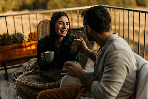 istock Young couple holding hands and drinking coffee on balcony at sunset 2214752155