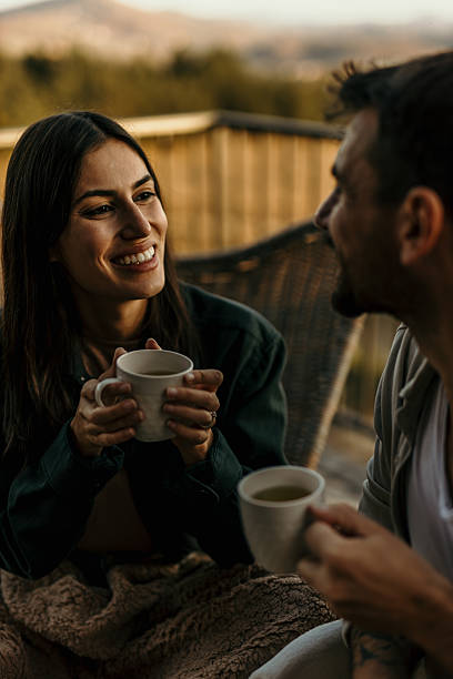 istock Young couple relaxing and drinking tea together on balcony at sunset 2214752165