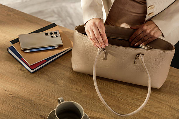 istock Female Hands Packing Purse at Desk – Workday Morning Routine. Getting to work real-life moment in a professional or home office setting. Everyday and lifestyle activities concept. 2214752285