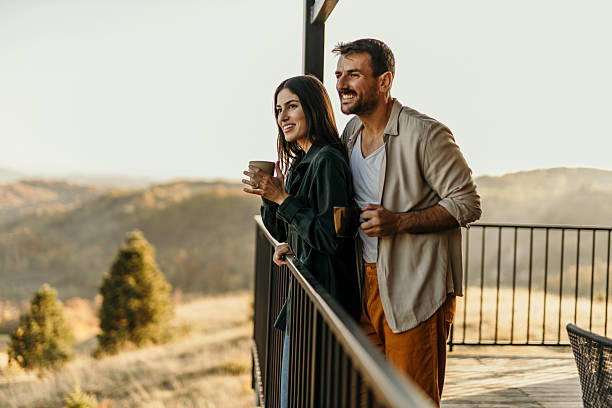 istock Smiling couple drinking coffee and enjoying mountain view from balcony 2214752417
