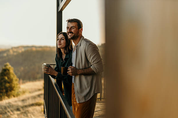 istock Happy couple enjoying morning coffee on balcony with scenic view 2214752421