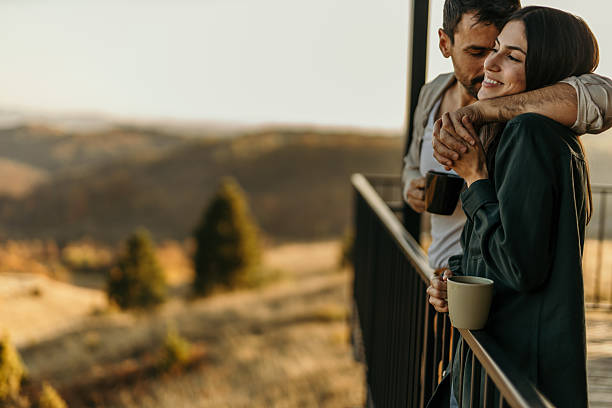 istock Couple embracing and drinking coffee on a balcony with a mountain view 2214752464