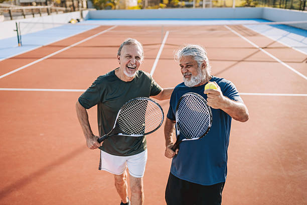 istock two senior friends playing tennis 2214755083