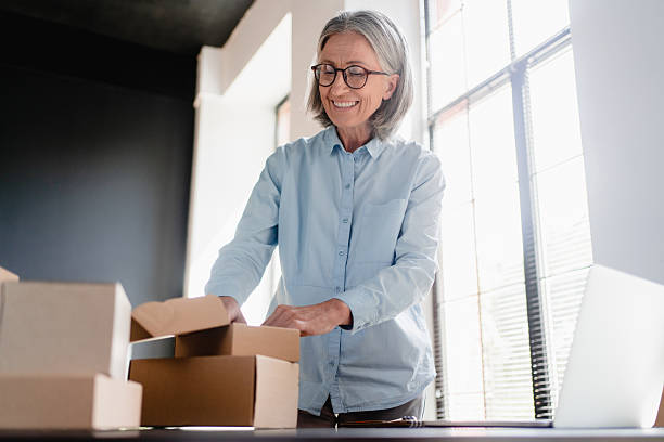 istock Low angle view of old female online store small business owner worker packing package post shipping ecommerce retail order in box preparing delivery parcel on table. Dropshipping service. 2214760164