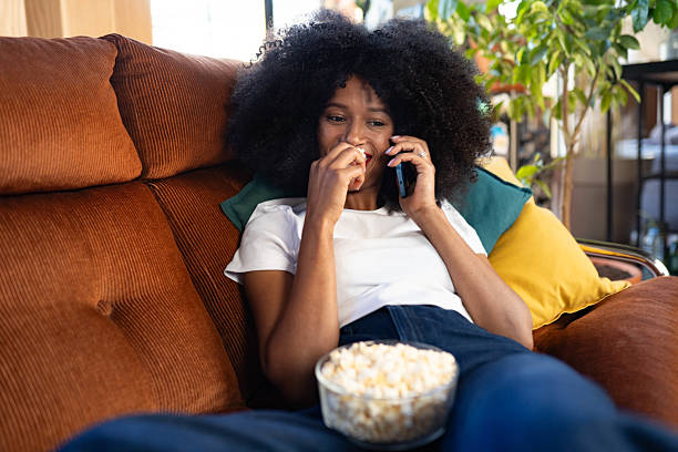 istock Happy Young Black Female Using Smartphone While Lying On Comfy Sofa At Home 2214764605