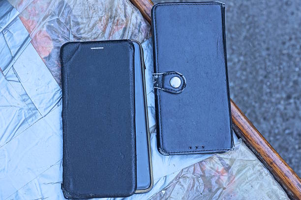 two smartphones in black leather closed cases lie in table on the street