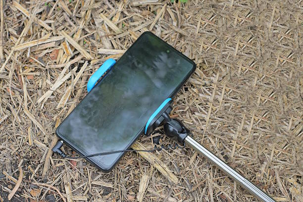 one black smartphone on a long selfie stick on a summer street