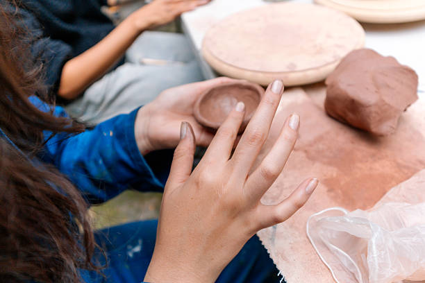 Potter creating a small terracotta bowl with dirty hands in a pottery workshop, showcasing the artistry and skill involved in handmade ceramics