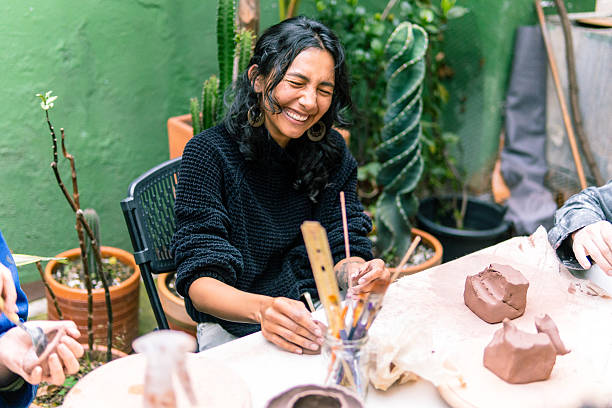 istock Young woman smiling while creating pottery outdoors 2214767698