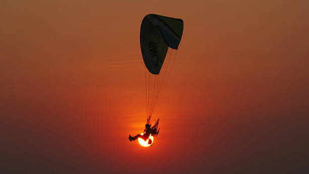 istock Motor paraglider flying through colorful sunset sky 2214768375