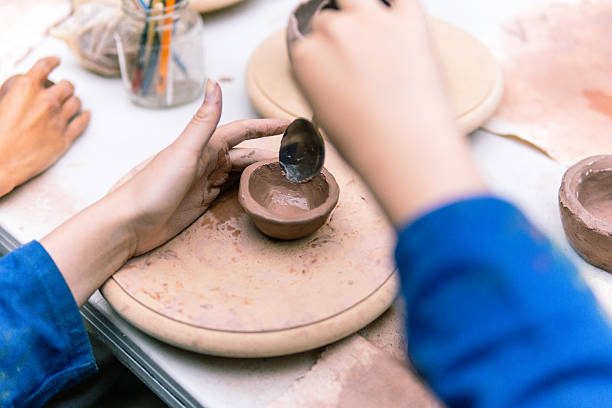 istock Potter using spoon smoothing clay of small bowl during pottery class 2214768663