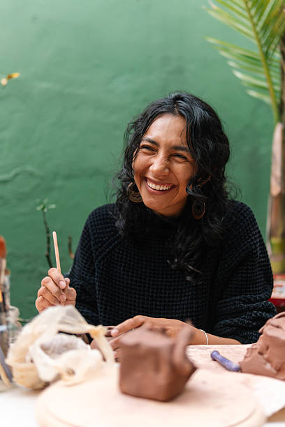 istock Latin american woman smiling and holding sculpting tool while creating pottery 2214770218