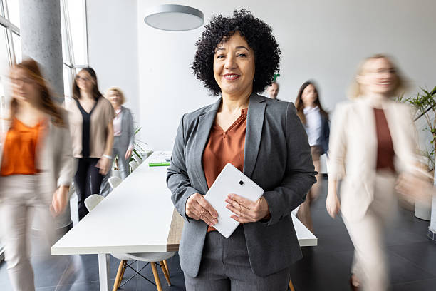 istock Cheerful businesswoman with tablet in busy office setting 2214771413