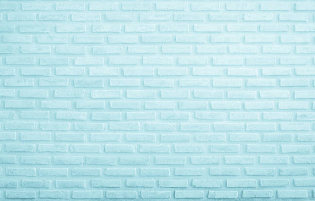 Brick wall painted with pale blue paint pastel calm tone texture background. Brickwork and stonework flooring interior rock old pattern clean concrete grid uneven bricks design stack backdrop.