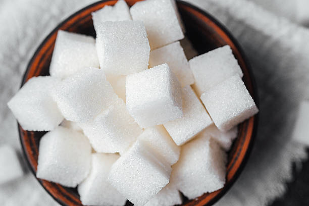 istock Sweet sugar cubes in a brown bowl on a textured cloth table 2214771997