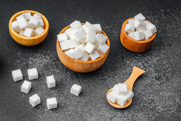 istock Sugar cubes in wooden bowls and a spoon on a dark surface 2214772002
