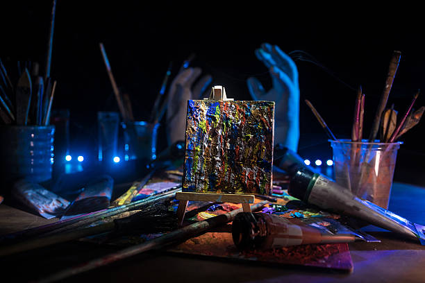 Art Concept with Brushes, Paints and Miniature Canvas in Moody Lighting. Selective focus