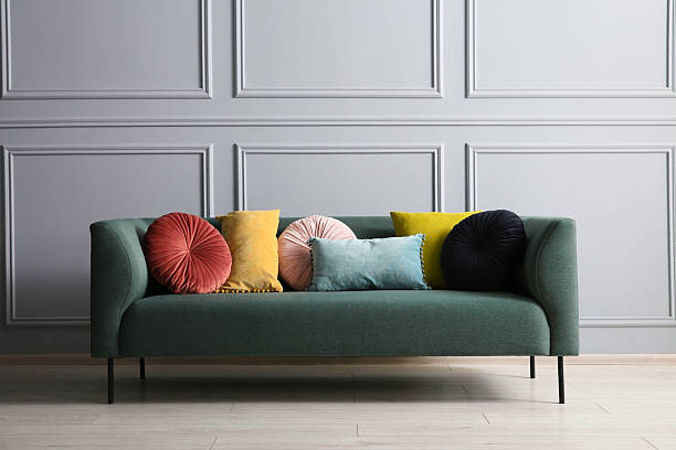 istock Stylish sofa with different cushions near grey wall 2214772478